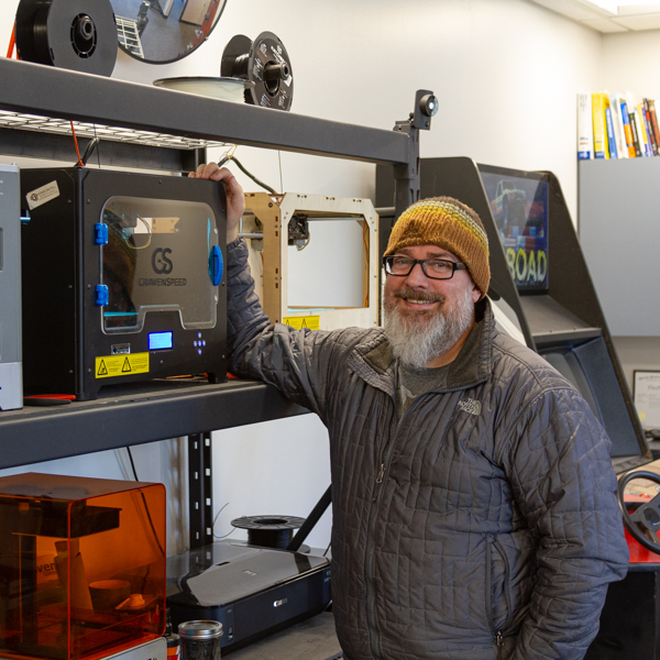 Steve standing in front of a rack fuill of 3D printers